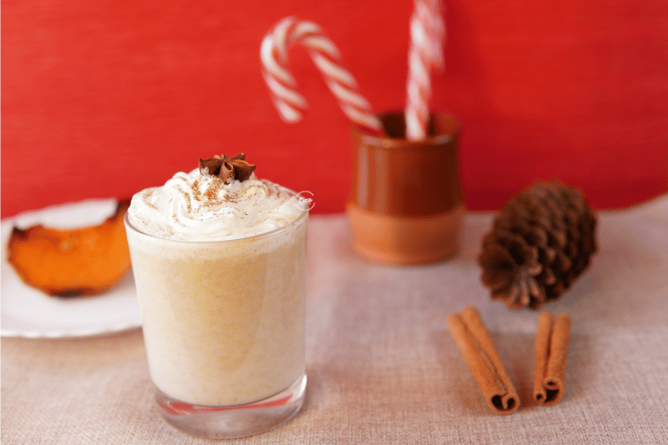 Napitak od bundeve u staklenoj čaši i štapići cimeta, Pumpkin spice chai in a glass with cinammon sticks on the table